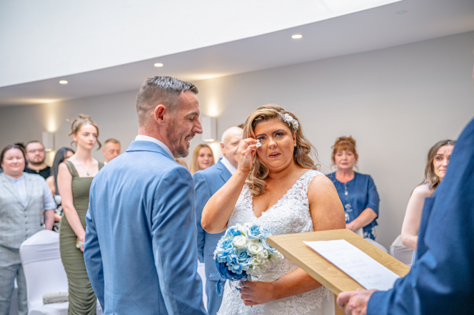 Couple saying their vows during a Bury Registry Office wedding as the bride wiping away a tear