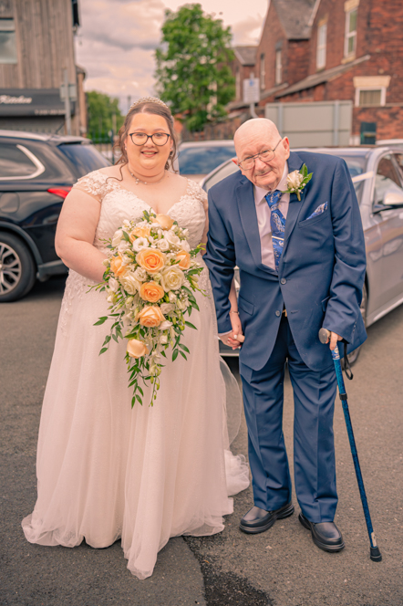 Bride and father of the bride standing in front of the wedding car