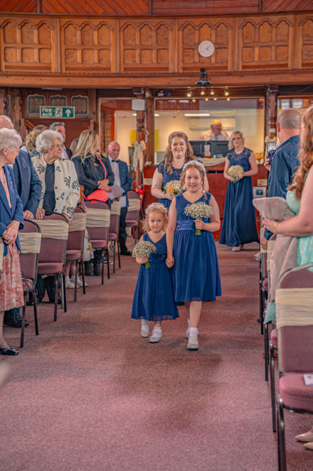 Bridesmaid and two flower girls walking down the aisle