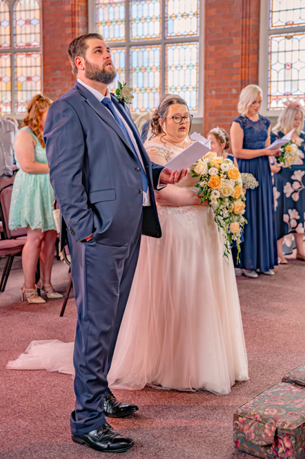 Bride, groom and wedding guests singing a hymn