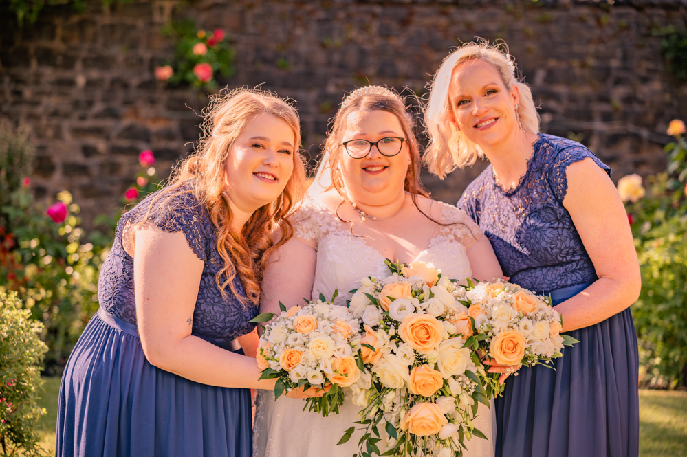 Bride and two bridesmaids holding their bouquets close together at a Greater Manchester wedding