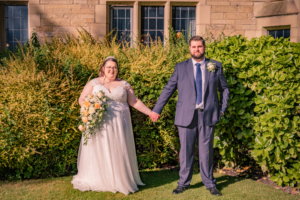 Bride and groom holding hands at a distance