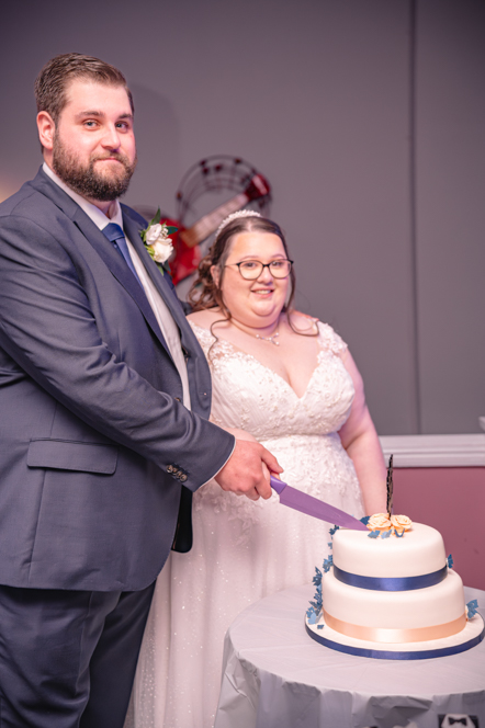 Bride and groom cutting wedding cake at reception in Bury