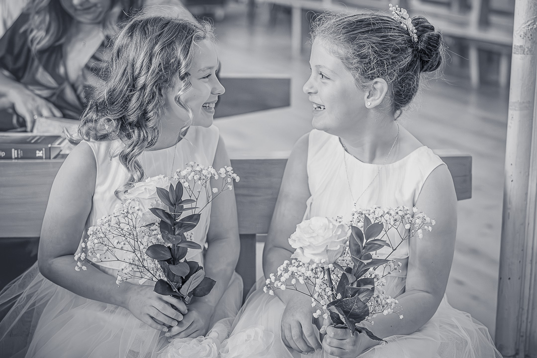 Two flower girls smiling at each other inside St Peter’s Church