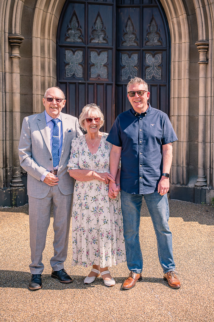 Older couple with their son outside St Peter’s Church, Ashton-under-Lyne, after traditional Christian wedding vow renewal
