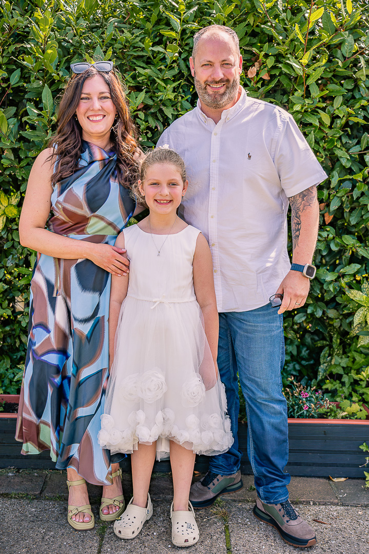 Mother and father standing with their young daughter for a portrait.