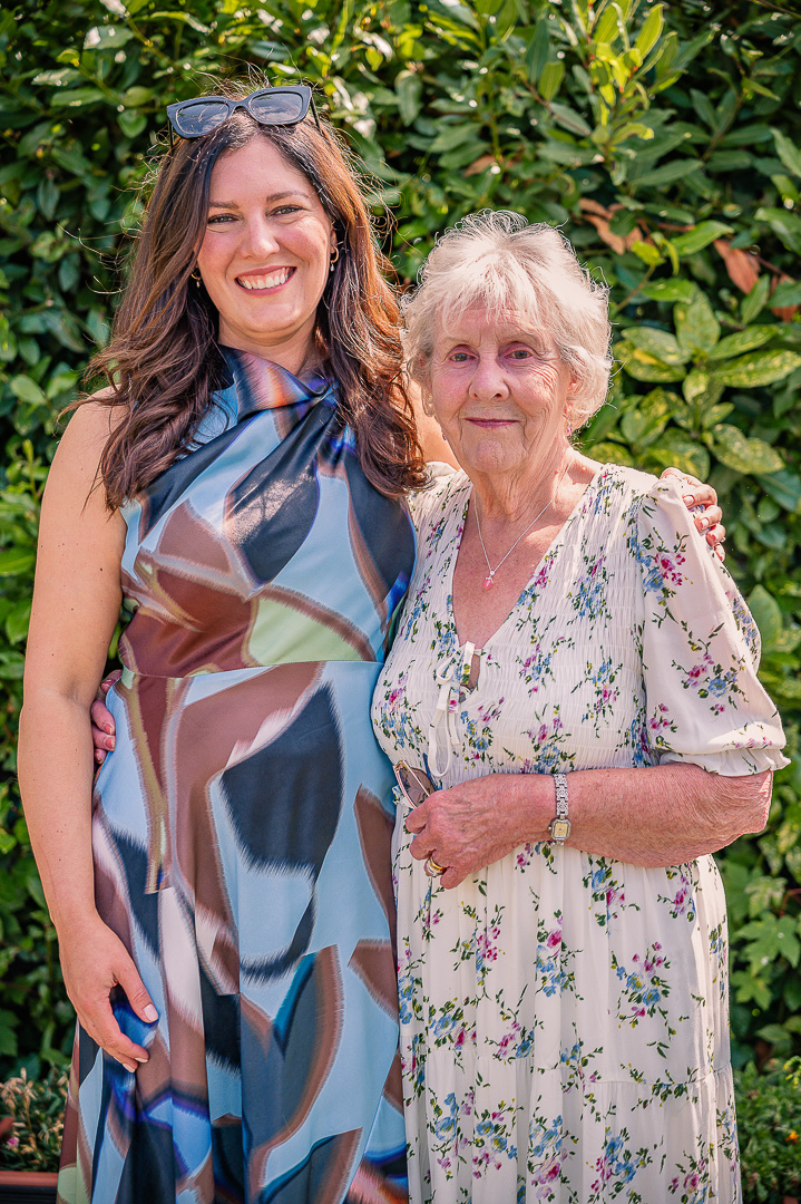 Elderly grandmother standing with her adult granddaughter for a portrait.