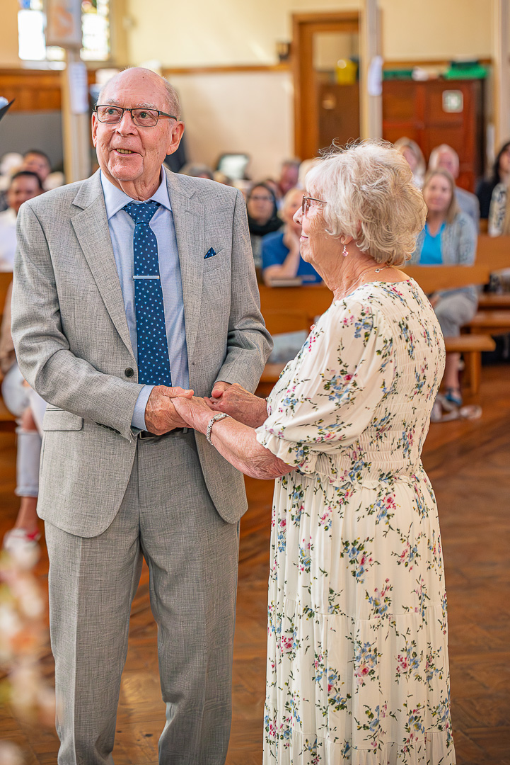 Holding hands as they renew their vows