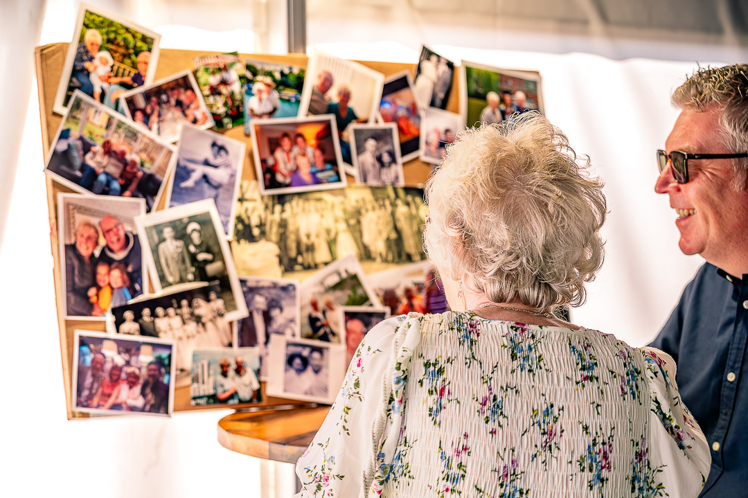 Two guests looking at a display board filled with family photographs.