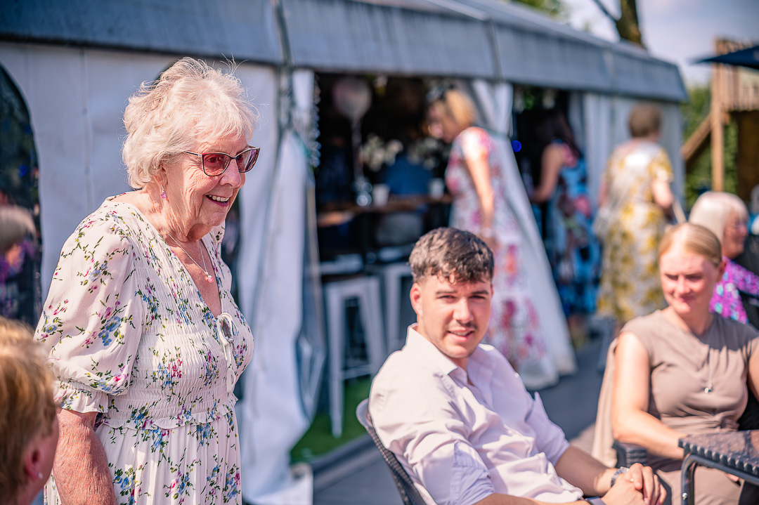 Wedding guests chatting together outside in the sunshine during the reception.