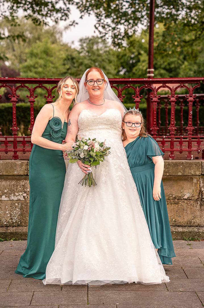 Bride with a bridesmaid and a junior bridesmaid standing together at Broadfield Park in Rochdale