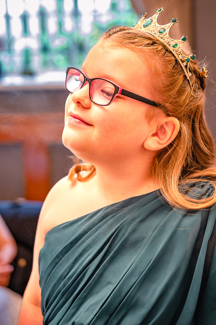 Close-up of a young bridesmaid in a green dress and tiara during morning preparations