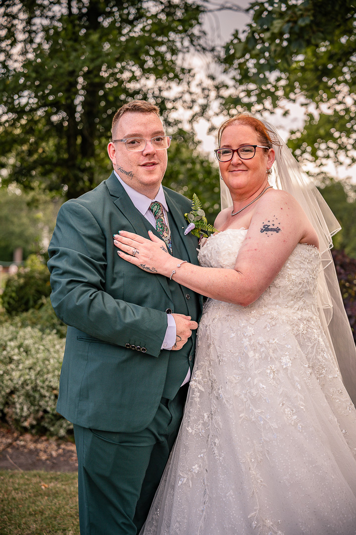Bride and groom together beneath the trees at Broadfield Park