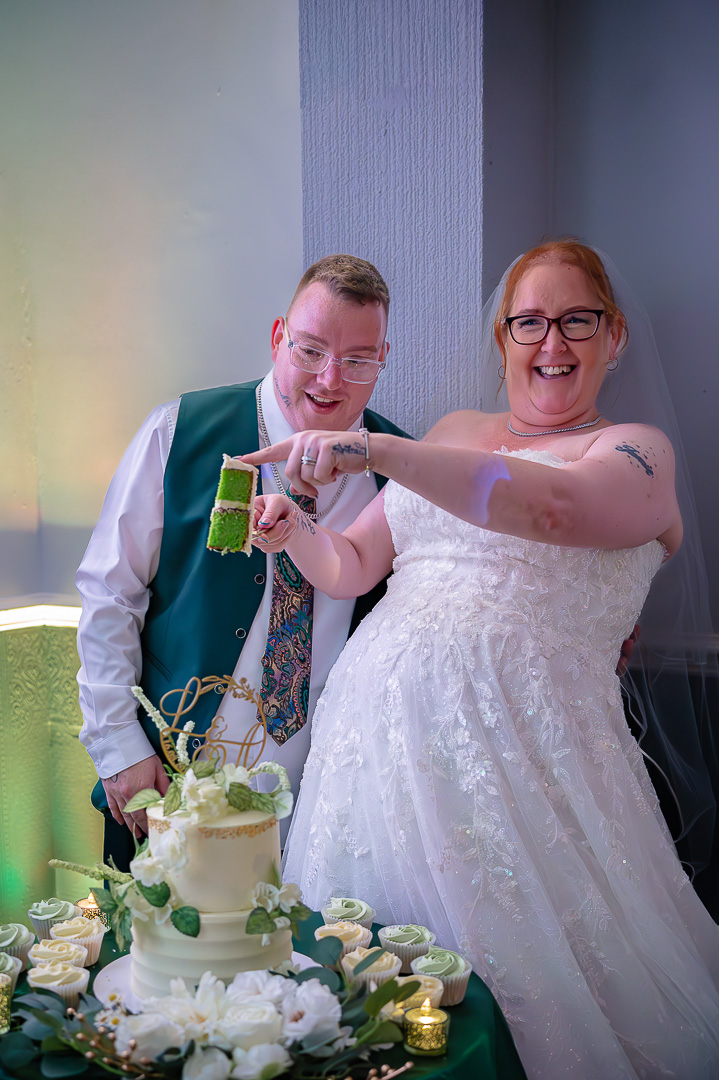 Bride and groom showing a slice of their green wedding cake during their elegant, classic wedding reception