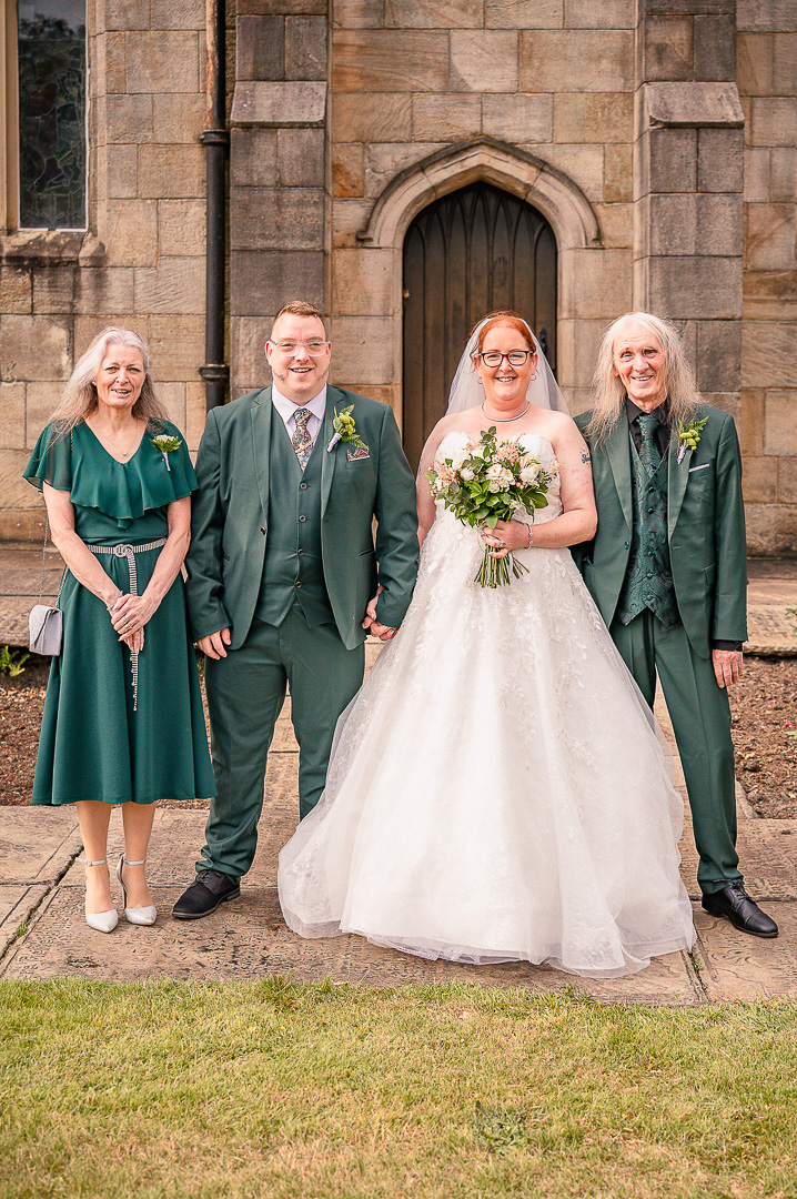 Bride and groom with the groom’s parents outside the church in Greater Manchester