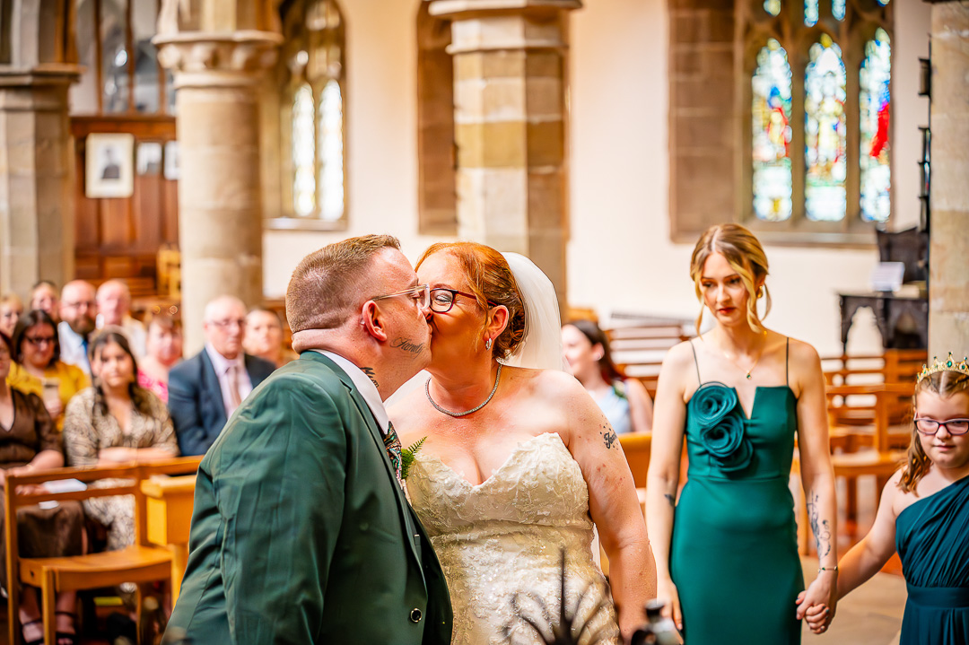 Bride and groom sharing their first kiss at St Chad’s Church in Rochdale