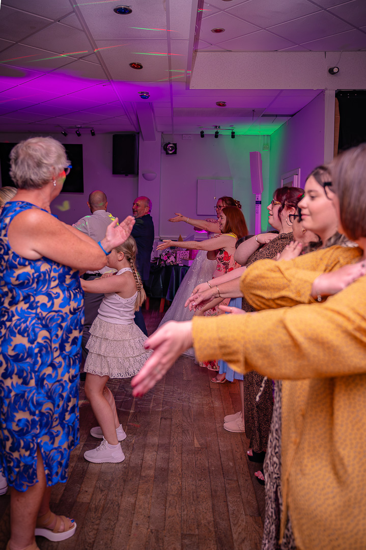 Bride and guests dancing together to the Macarena during a fun, traditional wedding reception at Bucks Bar