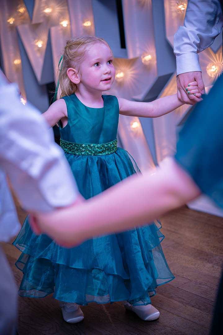 Young girl holding hands with others while dancing at Bucks Bar during a classic wedding celebration
