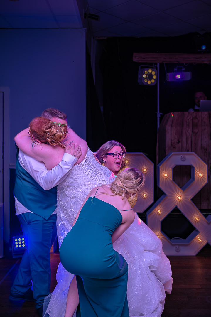 Two women lifting the bride off the ground as the groom holds her, capturing the playful, celebratory atmosphere of a classic wedding at Bucks Bar