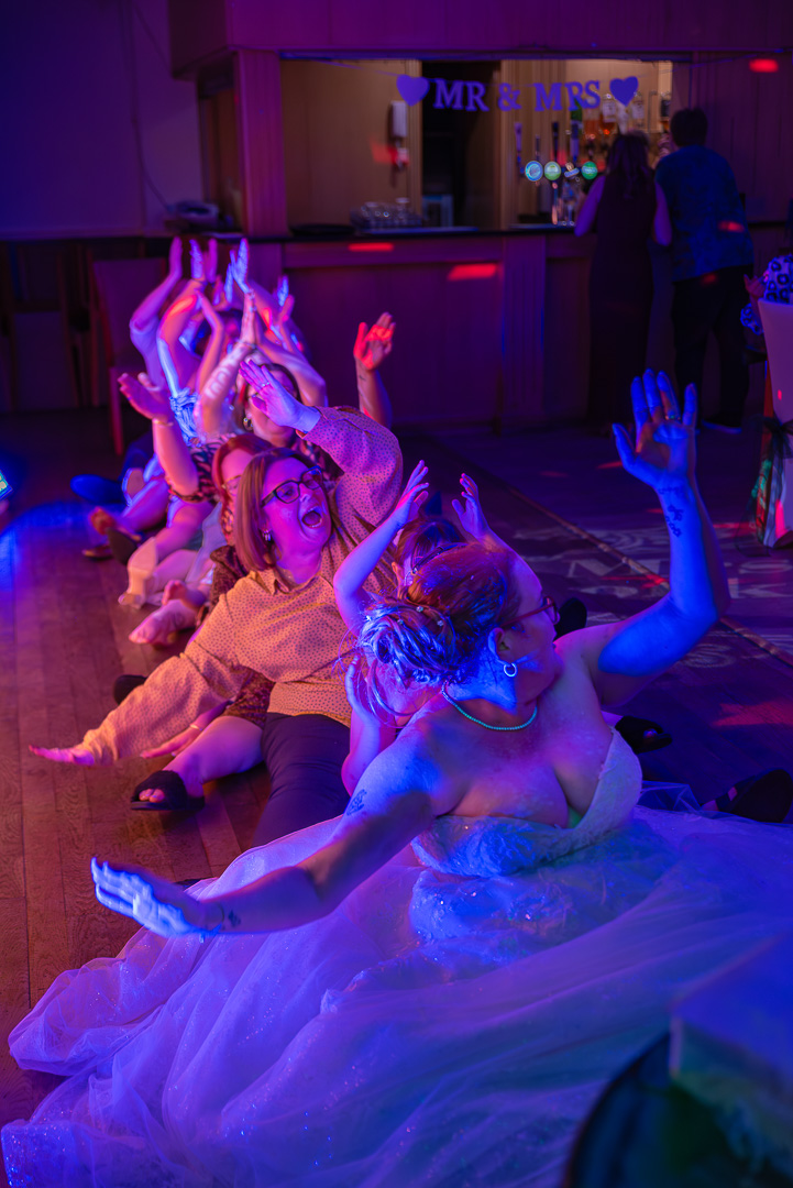 Bride and guests dancing together to the Cha Cha Slide during a fun and lively wedding reception at Bucks Bar
