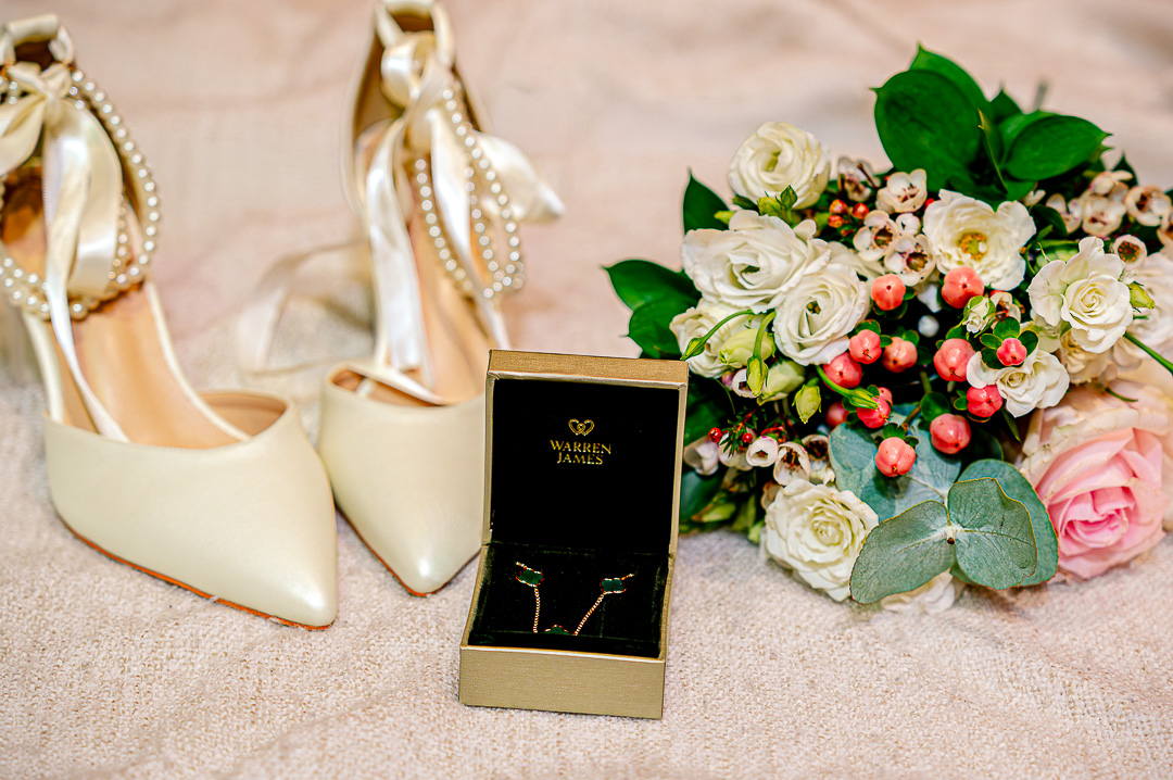 Bridal shoes, necklace and earrings arranged with bouquets during preparations at the Royal Toby Hotel in Rochdale