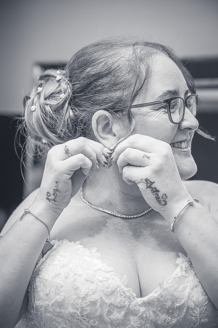 Bride putting on her earrings during the final moments of bridal preparations