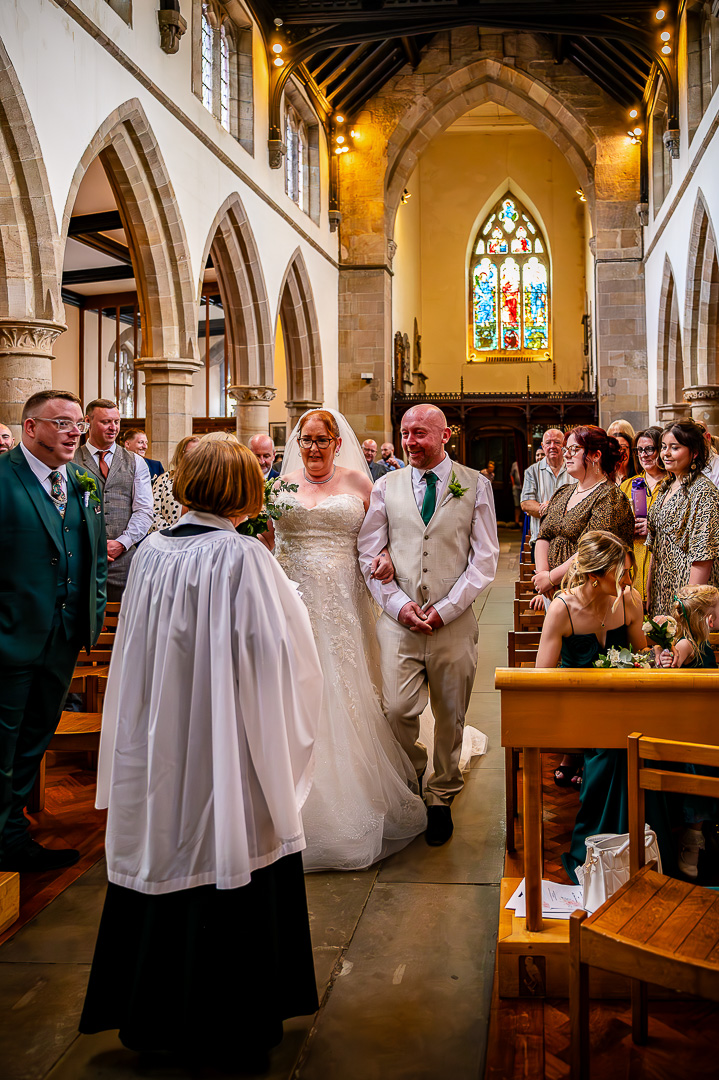 Bride walking down the aisle with her brother at St Chad’s Church in Rochdale