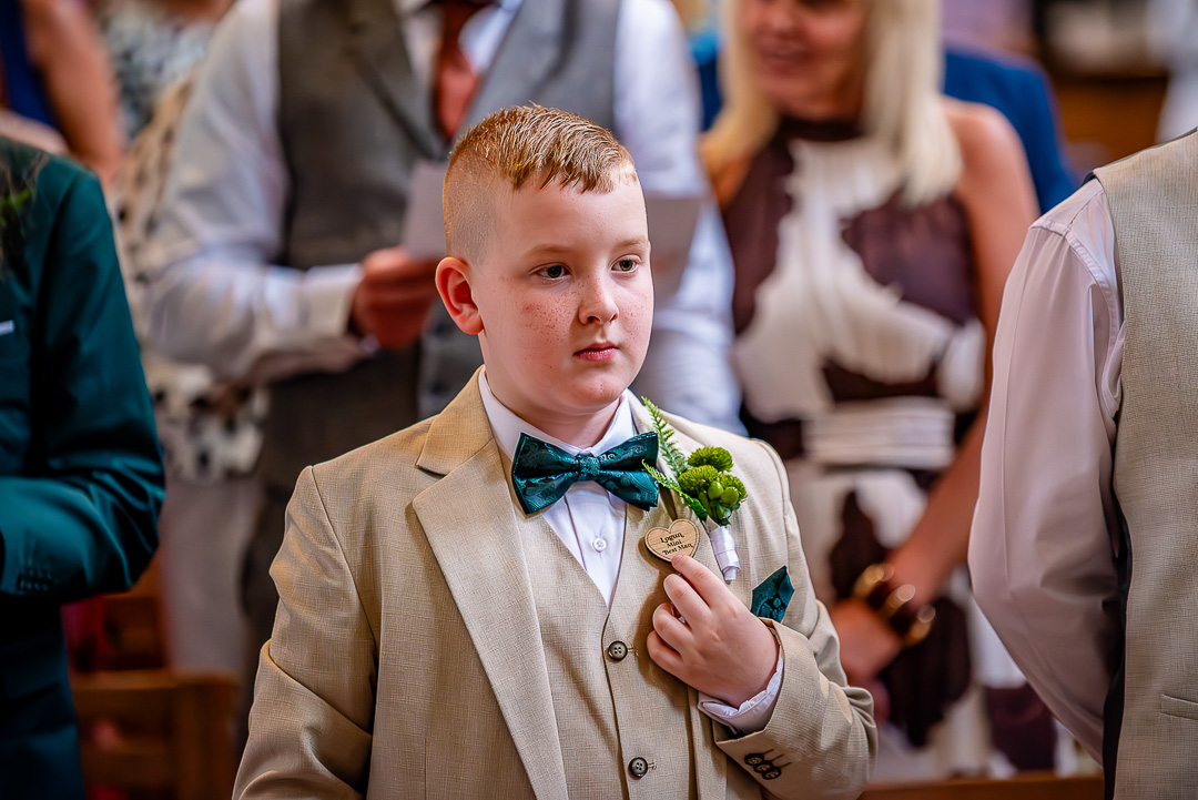 Young best man adjusting his badge during the wedding ceremony