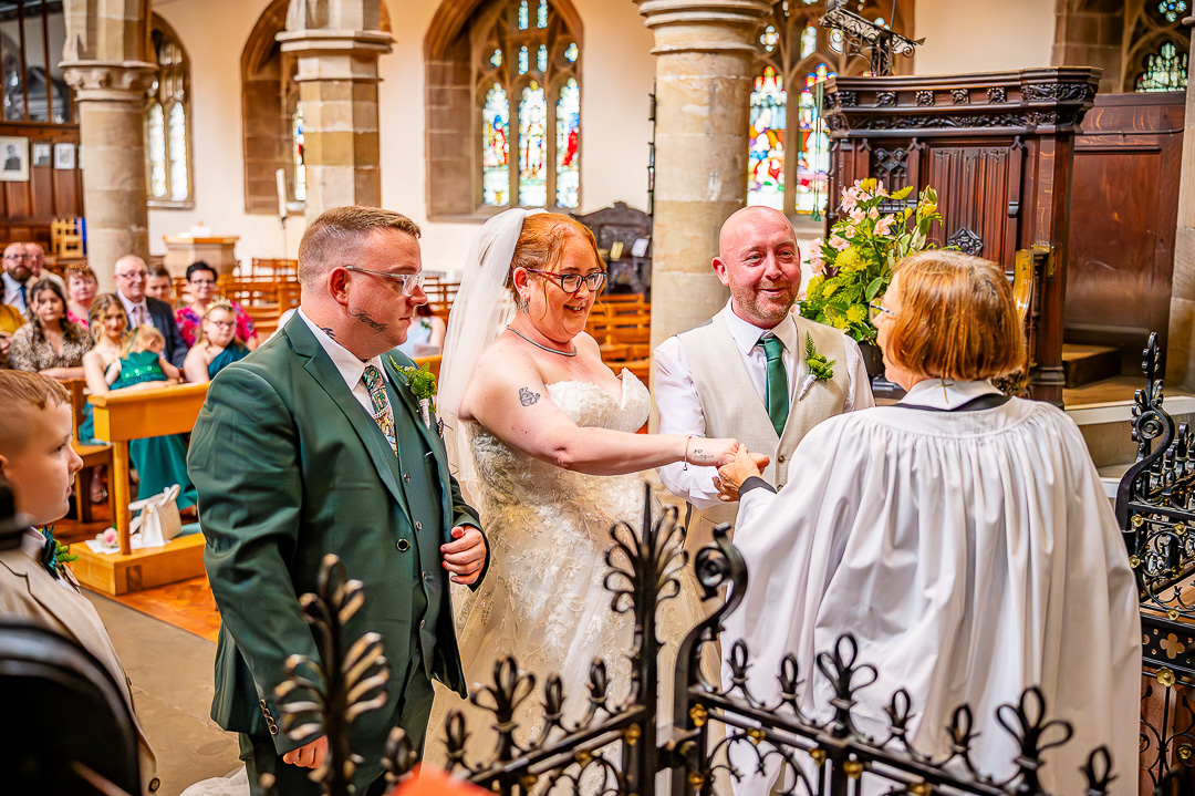 Brother of the bride giving her hand to the groom at the altar