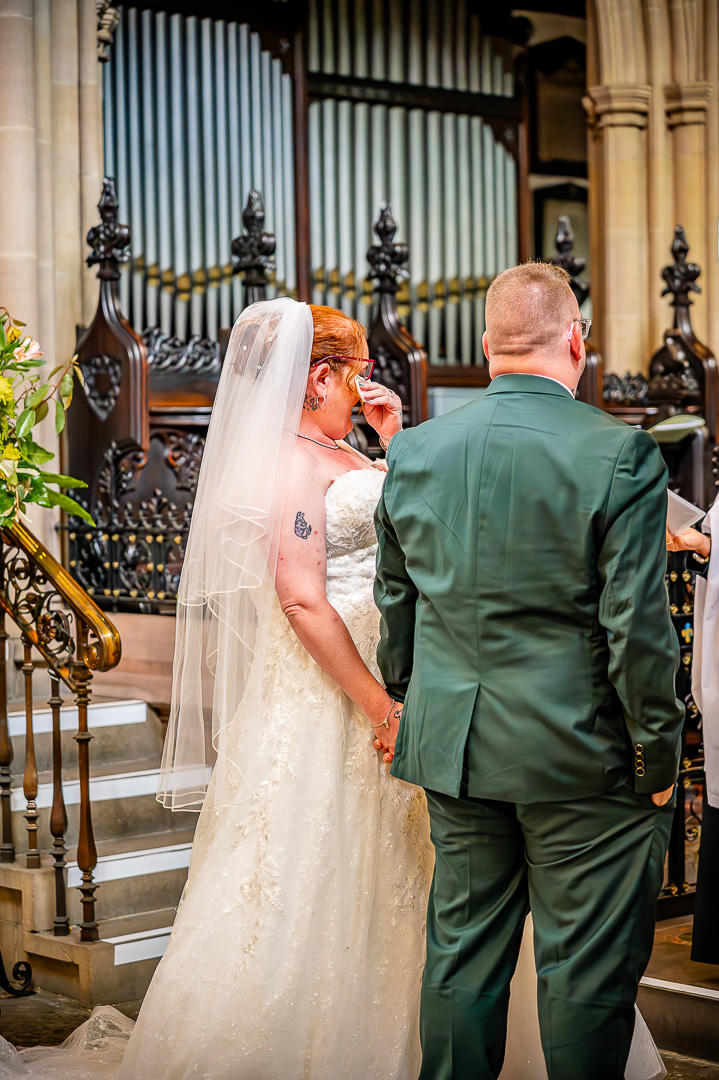 Back view of the bride wiping away a tear during the ceremony at St Chad’s Church