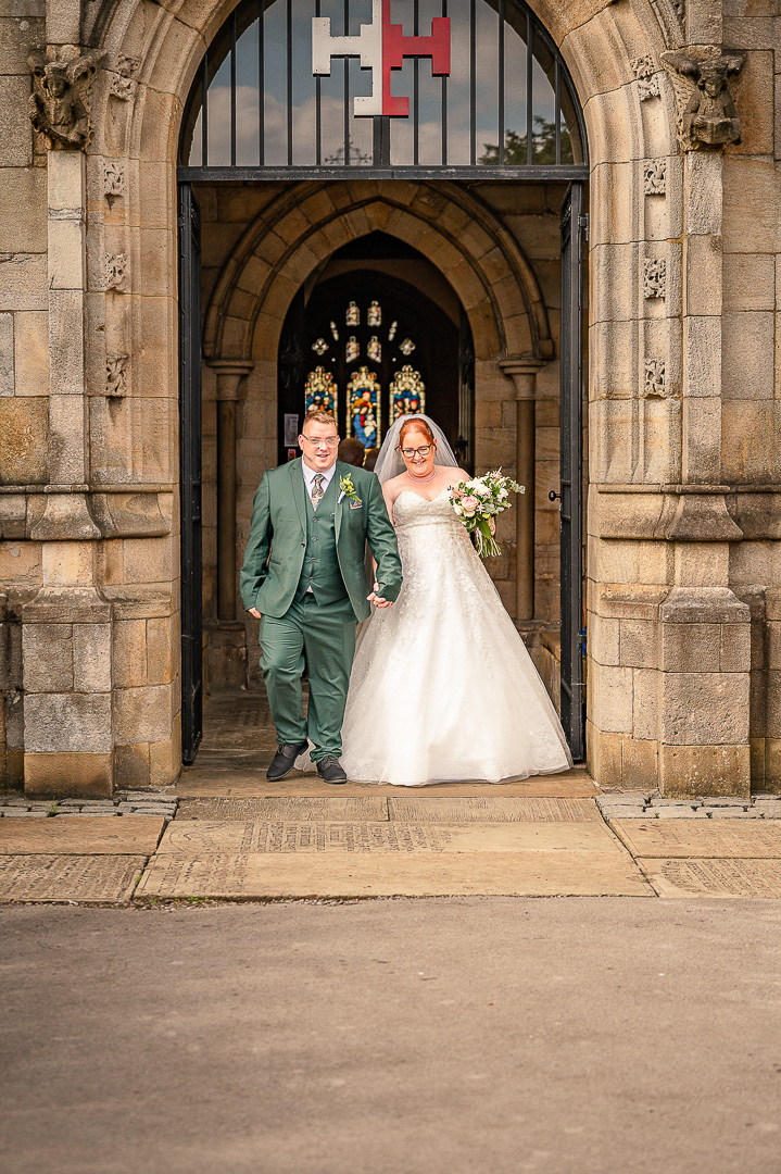 Bride and groom holding hands as they leave St Chad’s Church in Rochdale, Greater Manchester after their traditional Christian wedding
