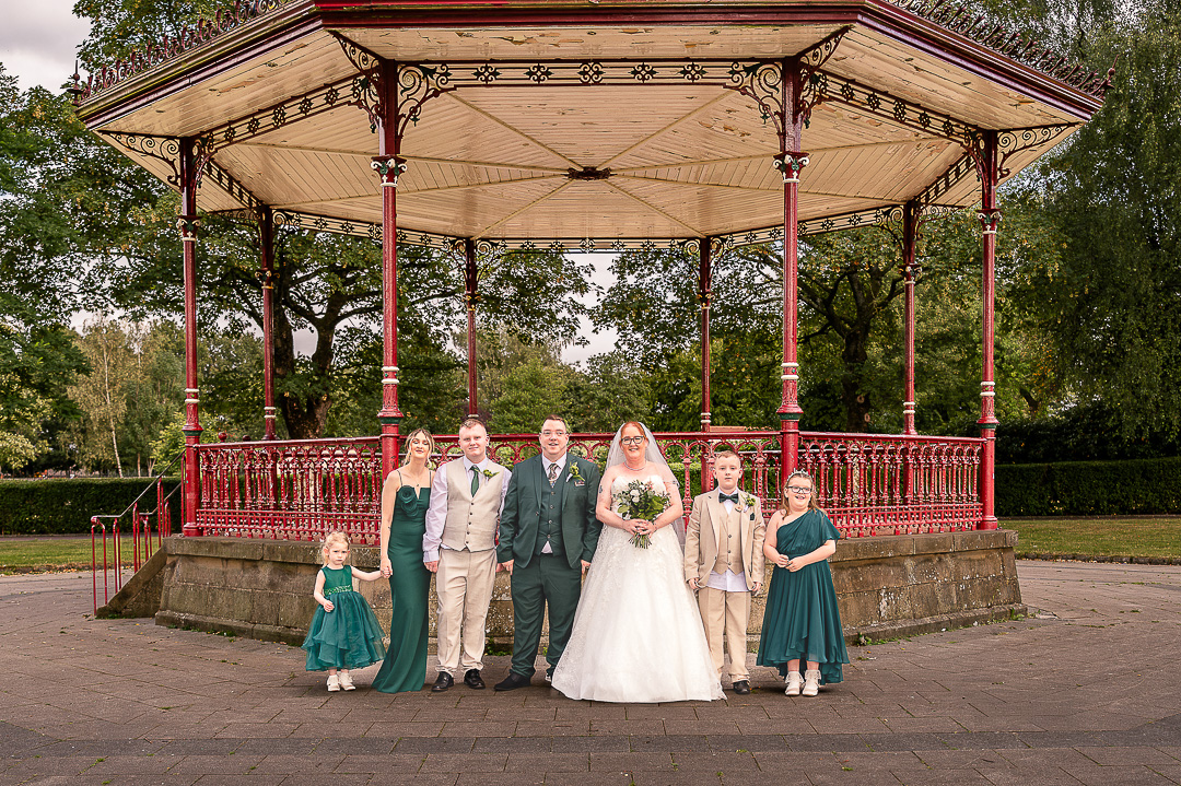 Manchester Wedding Photographer Rebekah Morecroft Photography812 portrait of bride and groom and there wedding party of two young bestmen, two young bridesmaid and adult bridesmaid with bandstand behind them