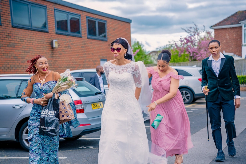 Bride arriving at William Hulme's Grammar School with her mother, sister and brother for her wedding blessing in Manchester