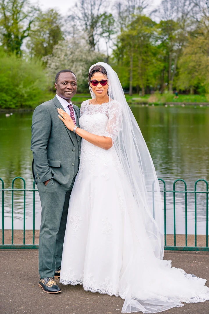 Couples portrait with lake behind them. Bride’s hand resting on groom's shoulder