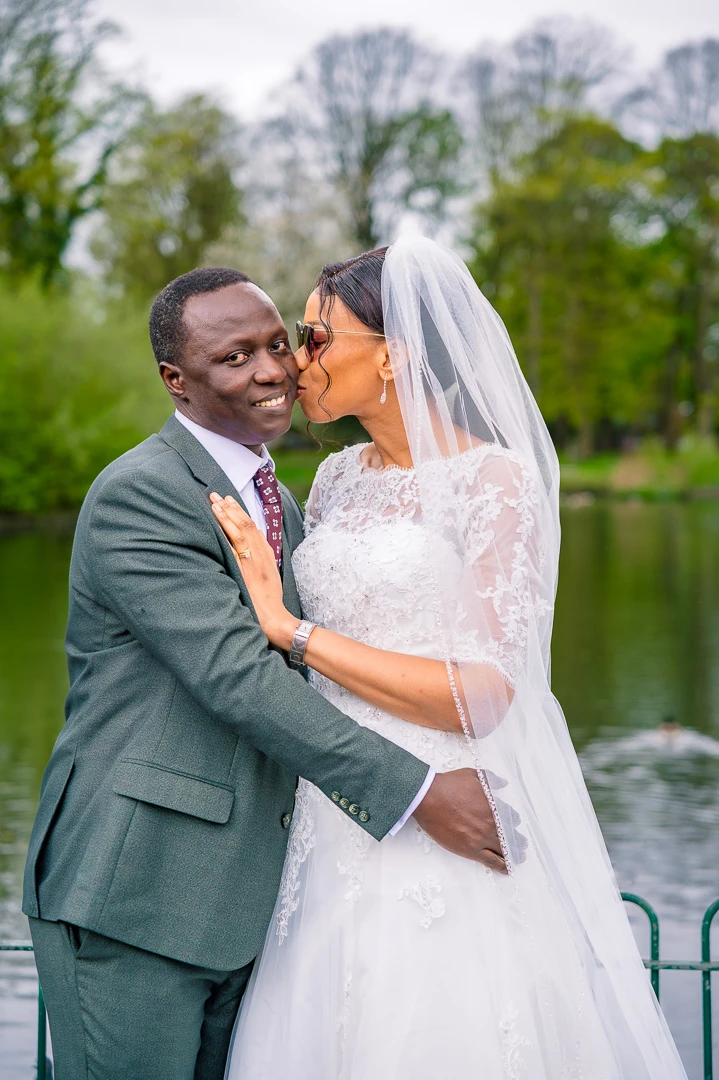 Bride kissing groom on the cheek during portraits at Alexandra Park Manchester